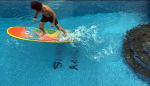 man is training on a surfboard in a pool