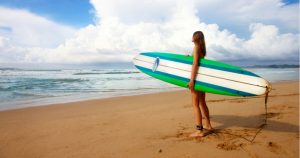 Woman stands on the beach with a surfboard